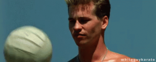 A Shirtless Man Is Balancing A Volleyball On His Fingertips . GIF