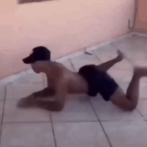 A Shirtless Man Is Crawling On The Floor With His Legs Crossed . GIF