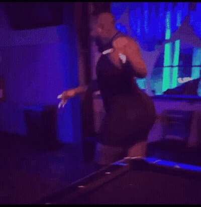 A Shirtless Man Is Dancing In A Dark Room With A Red Exit Sign . GIF
