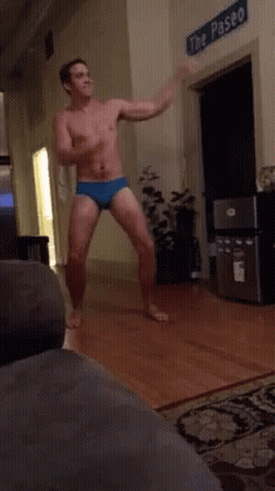 A Shirtless Man Is Dancing In A Living Room In Front Of A Sign That Says The Paseo GIF