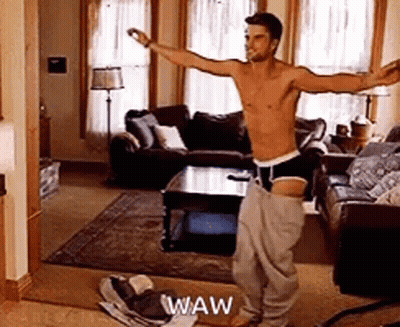 A Shirtless Man Is Dancing In A Living Room With His Arms Outstretched . GIF