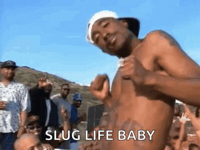 A Shirtless Man Is Dancing In Front Of A Crowd Of People With The Words `` Slug Life Baby '' Written On The Bottom . GIF