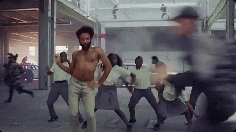 A Shirtless Man Is Dancing With A Group Of People . GIF