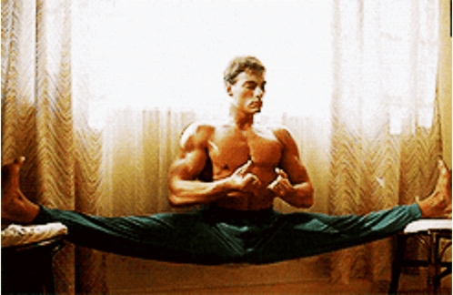 A Shirtless Man Is Doing A Split In Front Of A Window . GIF