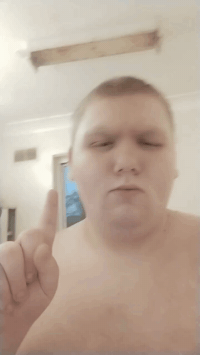 A Shirtless Man Is Giving A Thumbs Up In Front Of A Window GIF