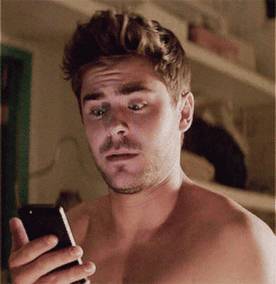 A Shirtless Man Is Holding A Cell Phone In His Hand GIF