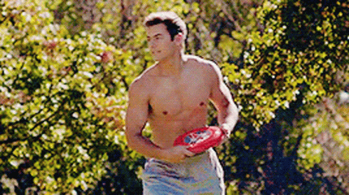 A Shirtless Man Is Holding A Frisbee In His Hand GIF