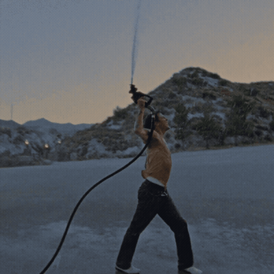 A Shirtless Man Is Holding A Hose In His Hand GIF