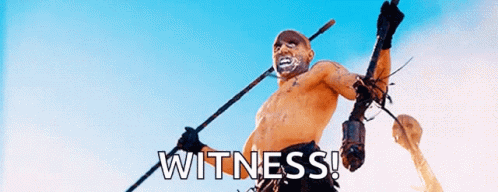 A Shirtless Man Is Holding A Spear And The Word Witness Is On The Bottom Right GIF