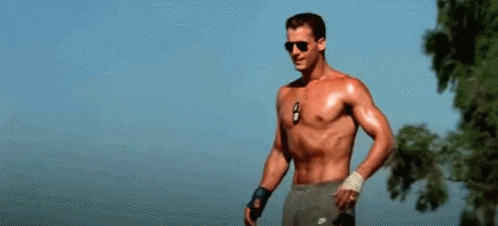 A Shirtless Man Is Holding A Volleyball In His Hand . GIF
