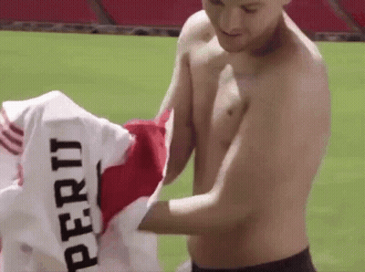 A Shirtless Man Is Holding Up A Jersey That Says Peru GIF