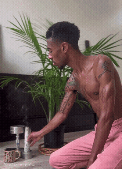 A Shirtless Man Is Kneeling Down In Front Of A Potted Plant With The Name Kalvinkosha On The Bottom Right GIF
