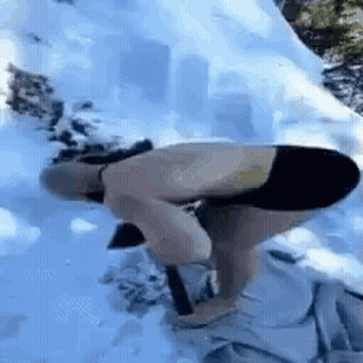 A Shirtless Man Is Kneeling Down In The Snow Holding A Shovel . GIF
