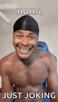 A Shirtless Man Is Laughing And Smiling While Wearing A Beanie . GIF
