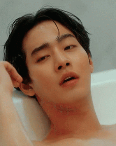 A Shirtless Man Is Laying In A Bathtub With His Mouth Open GIF