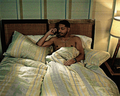 A Shirtless Man Is Laying In Bed Talking On A Phone GIF
