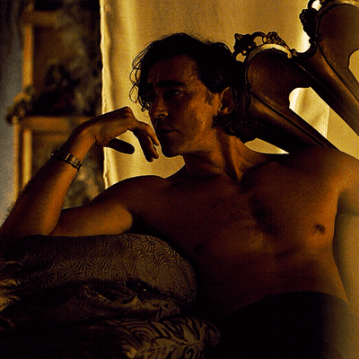 A Shirtless Man Is Laying On A Bed With His Hand On His Face GIF
