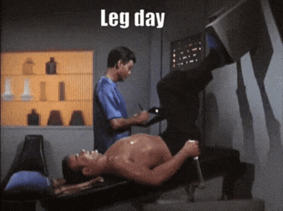 A Shirtless Man Is Laying On A Bench While Another Man Writes On A Clipboard With The Words Leg Day Below Him GIF