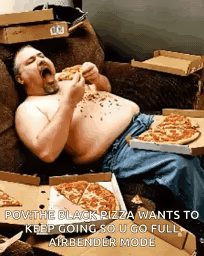 A Shirtless Man Is Laying On A Couch Eating Pizza GIF