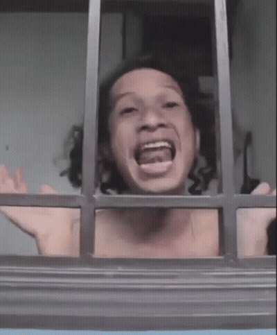 A Shirtless Man Is Looking Out Of A Window With His Mouth Open And His Arms Outstretched . GIF