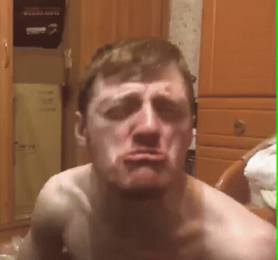 A Shirtless Man Is Making A Funny Face While Sitting On A Chair In A Room . GIF