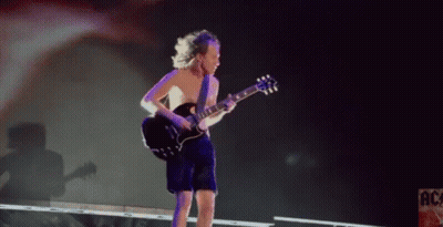 A Shirtless Man Is Playing A Guitar On Stage In Front Of A Sign That Says Ac GIF