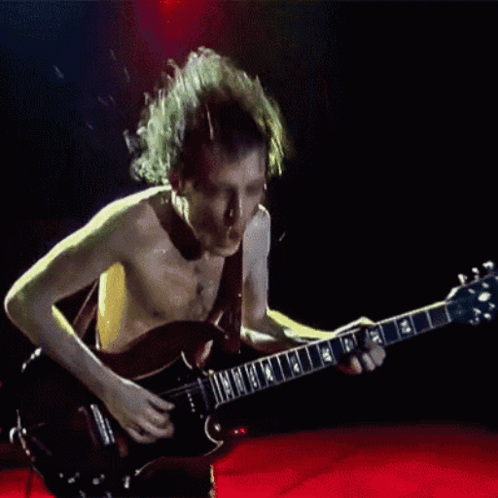 A Shirtless Man Is Playing A Guitar With The Letters Nm On It GIF