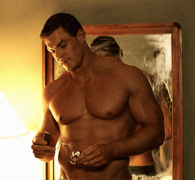 A Shirtless Man Is Shaving His Beard In Front Of A Mirror GIF