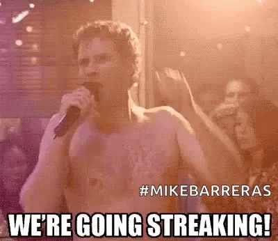 A Shirtless Man Is Singing Into A Microphone In Front Of A Crowd At A Concert . GIF
