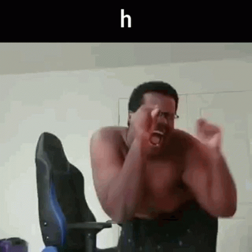 A Shirtless Man Is Sitting In A Chair With His Hands In The Air And Screaming . GIF