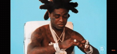 A Shirtless Man Is Sitting In A Chair With The Letter A On The Bottom GIF