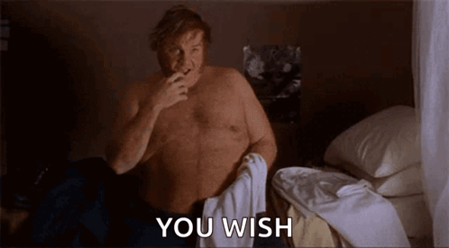 A Shirtless Man Is Sitting On A Bed With A Toothbrush In His Mouth And The Words `` You Wish '' Behind Him . GIF