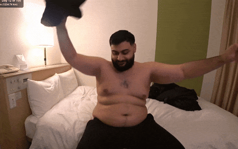 A Shirtless Man Is Sitting On A Bed With His Arms Outstretched In Front Of A Screen That Says Day 12 Of 100 GIF