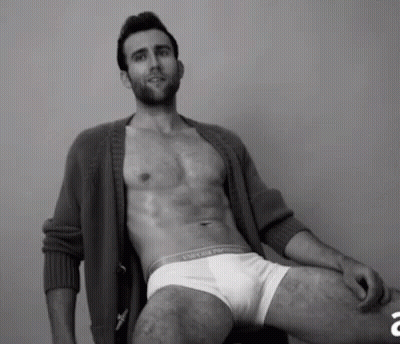 A Shirtless Man Is Sitting On A Chair Wearing White Underwear And A Cardigan . GIF
