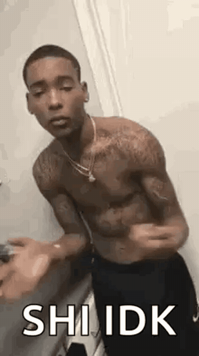 A Shirtless Man Is Standing In A Bathroom With His Arms Outstretched And A Necklace Around His Neck . GIF