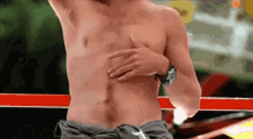 A Shirtless Man Is Standing In A Boxing Ring With His Hand On His Chest . GIF