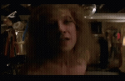 A Shirtless Man Is Standing In A Closet Holding A Bottle GIF