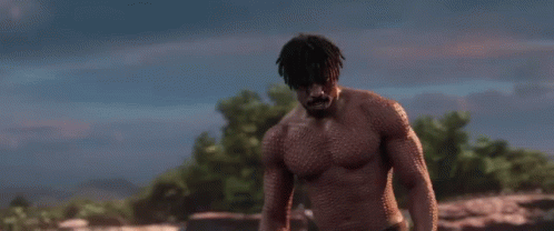 A Shirtless Man Is Standing In A Field With The Words `` Is This Your King ? '' Written On The Screen . GIF