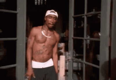 A Shirtless Man Is Standing In Front Of A Door Wearing A White Hat . GIF