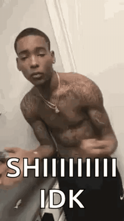A Shirtless Man Is Standing In Front Of A Door With His Arms Outstretched And A Necklace Around His Neck . GIF