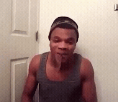 A Shirtless Man Is Standing In Front Of A Door With His Tongue Sticking Out . GIF
