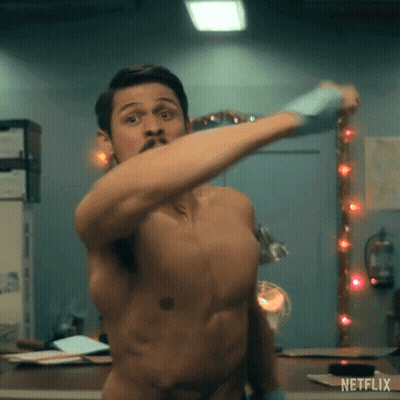 A Shirtless Man Is Standing In Front Of A Mirror And Holding A Hammer . GIF