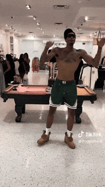 A Shirtless Man Is Standing In Front Of A Pool Table In A Store GIF
