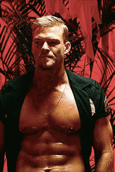 A Shirtless Man Is Standing In Front Of A Red Wall With A Palm Tree In The Background GIF