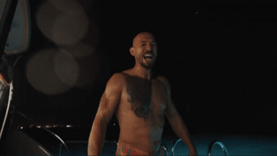A Shirtless Man Is Standing In Front Of A Sign That Says Edom GIF