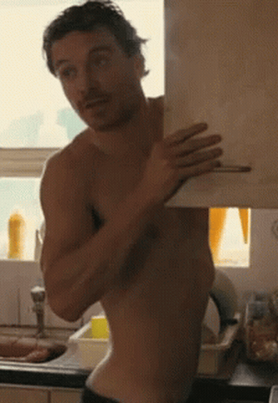 A Shirtless Man Is Standing In Front Of A Sink Holding A Piece Of Paper GIF