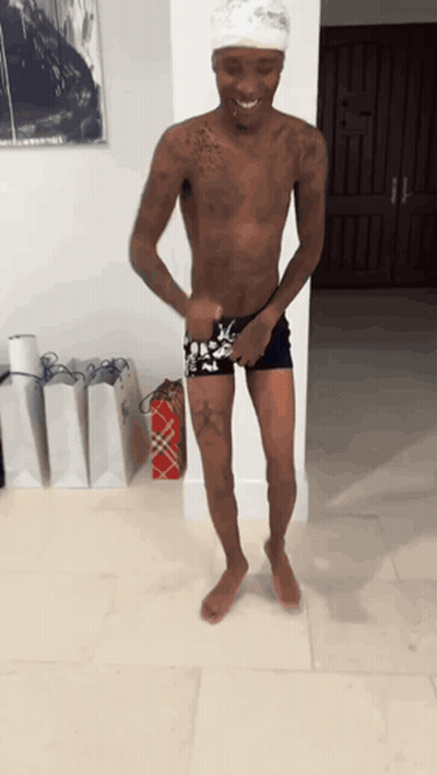A Shirtless Man Is Standing In Front Of A Wall With A Picture On It GIF