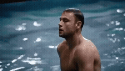 A Shirtless Man Is Standing In The Water With His Eyes Closed . GIF
