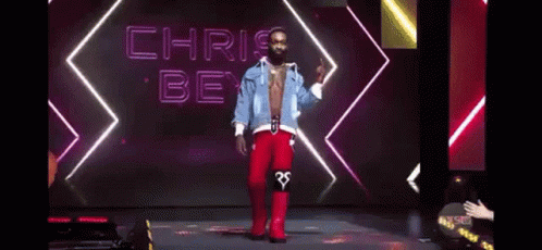 A Shirtless Man Is Standing On A Stage With His Tongue Out . GIF