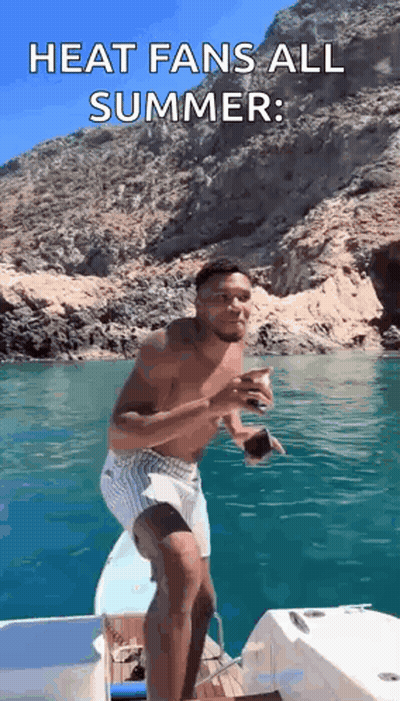A Shirtless Man Is Standing On The Side Of A Boat In The Ocean . GIF